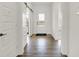 Bright hallway with hardwood floors, white walls, sliding barn door, and view of the front door at 15344 Cardonia Rd, Fishers, IN 46037