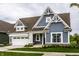 Charming home featuring blue siding, a brown roof, a white garage door and beautifully landscaped front yard at 15596 Edenvale Dr, Westfield, IN 46074