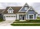 Charming home featuring blue siding, a brown roof, a white garage door and beautifully landscaped front yard at 15596 Edenvale Dr, Westfield, IN 46074