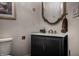 Stylish powder room features black vanity, marble countertop, and unique gold trimmed mirror at 1894 Rhettsbury St, Carmel, IN 46032