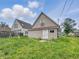 Exterior view of the back of the home with overgrown grass in need of repair at 1947 N Parker Ave, Indianapolis, IN 46218