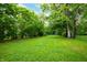 Expansive green backyard surrounded by mature trees with a house visible in the distance at 2402 Adams St, Indianapolis, IN 46218