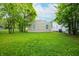 View of a large, grassy backyard featuring a neutral-colored house surrounded by mature trees at 2402 Adams St, Indianapolis, IN 46218
