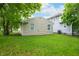 A green backyard features an outbuilding with tan siding and an adjacent gray house at 2402 Adams St, Indianapolis, IN 46218
