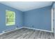 Cozy bedroom with ample natural light from the window and stylish gray wood-look flooring at 2402 Adams St, Indianapolis, IN 46218
