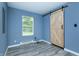Bedroom with modern sliding barn door, gray flooring, and a window providing natural light at 2402 Adams St, Indianapolis, IN 46218