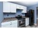 Well-equipped kitchen with stainless steel appliances, white cabinets, dark countertops, and modern gray flooring at 2402 Adams St, Indianapolis, IN 46218