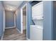 Hallway view of the laundry room featuring a stacked washer and dryer unit, with modern gray walls and flooring at 2402 Adams St, Indianapolis, IN 46218