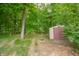Private backyard shed with a sturdy door surrounded by the natural beauty of a wooded area at 2875 Prairie Stream Way, Columbus, IN 47203