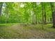 Wooded backyard featuring mature trees and custom log seating around a fire pit area at 2875 Prairie Stream Way, Columbus, IN 47203
