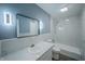 Updated bathroom with marble-look tile, modern mirror, and shower-tub combination at 3457 W 58Th St, Indianapolis, IN 46228