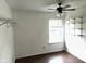 A white bedroom features a window, hardwood floors, a ceiling fan, and shelving at 4456 Redcliff N Ln, Plainfield, IN 46168