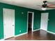 A bedroom features wood floors, bold green walls, a ceiling fan, and white trim at 4456 Redcliff N Ln, Plainfield, IN 46168