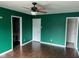 A bedroom features wood floors, bold green walls, a ceiling fan, and multiple doors at 4456 Redcliff N Ln, Plainfield, IN 46168