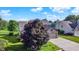 Scenic exterior view of a well-maintained home with a large tree, attached garage and neighborhood setting at 4506 Tarragon Dr, Indianapolis, IN 46237