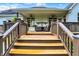 Stairs lead up to a covered deck with seating area, ceiling fans, and white brick columns at 6672 Braemar S Ave, Noblesville, IN 46062