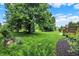 Lush backyard with grassy lawn, mature trees, landscaping, and a view of the wood deck at 6672 Braemar S Ave, Noblesville, IN 46062