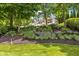 Beautiful landscaping with blooming flowers leads up to the charming house in a serene, wooded setting at 7016 Royal Oakland Way, Indianapolis, IN 46236