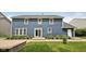 Back exterior view shows a beautiful home with a stone patio, manicured garden beds, and a lush green lawn at 8241 Holmard Pl, Indianapolis, IN 46259