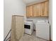 Functional laundry room with washer, dryer, storage cabinets, and neutral-colored tile flooring at 8241 Holmard Pl, Indianapolis, IN 46259
