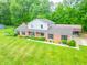 Elevated view of the property, highlighting its traditional exterior, expansive lawn, and convenient carport in a wooded area at 8772 W Evergreen Dr, Columbus, IN 47201