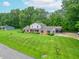 Aerial view of a brick and siding home, showcasing its large yard, carport, and wooded surroundings at 8772 W Evergreen Dr, Columbus, IN 47201