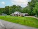 Brick and siding home with a carport boasts a well-kept lawn and is surrounded by lush trees, providing a suburban charm at 8772 W Evergreen Dr, Columbus, IN 47201