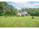 Landscaped lawn leads to the home's exterior, featuring brick accents and a backdrop of lush, mature trees at 8772 W Evergreen Dr, Columbus, IN 47201