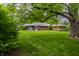 Backyard view of brick house with large tree and lush lawn at 8905 Washington Blvd West Dr, Indianapolis, IN 46240