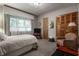 Bedroom featuring a large window with curtains, wood closet doors, and a cozy chair at 8905 Washington Blvd West Dr, Indianapolis, IN 46240