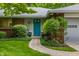 Charming home featuring a brick exterior, well-manicured bushes, and a bright blue front door at 8905 Washington Blvd West Dr, Indianapolis, IN 46240
