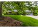 Charming home featuring a brick exterior, grey roof, lush greenery, and a manicured lawn at 8905 Washington Blvd West Dr, Indianapolis, IN 46240
