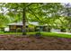 Charming home featuring a brick exterior, grey roof, lush greenery, and a quaint front bench at 8905 Washington Blvd West Dr, Indianapolis, IN 46240