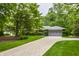 Charming home featuring a brick exterior, grey roof, lush greenery, and a paved driveway at 8905 Washington Blvd West Dr, Indianapolis, IN 46240