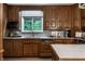 Well-lit kitchen featuring a window over the sink, wooden cabinets and light countertops at 8905 Washington Blvd West Dr, Indianapolis, IN 46240