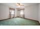 Bedroom with green carpet, white walls, ceiling fan and two windows with curtains at 924 N Devon Ave, Indianapolis, IN 46219