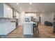 Bright kitchen with white cabinetry, stainless appliances, a central island with seating, and an open view to the living room at 9741 Haughton Ln, McCordsville, IN 46055