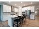 A modern kitchen features white cabinets, stainless steel appliances, an island with bar seating, and light wood flooring at 9741 Haughton Ln, McCordsville, IN 46055