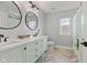 Stylish bathroom boasts double sinks, round mirrors, modern fixtures, and appealing flooring at 9917 Gallop Ln, Fishers, IN 46040