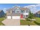 Inviting two-story home features a red front door, brick accents and attached three-car garage at 9917 Gallop Ln, Fishers, IN 46040