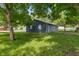 Backyard with a view of the blue house under the shade of a large tree at 1002 Collier St, Indianapolis, IN 46241