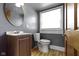 Bathroom featuring a vanity, toilet, round mirror, and window with blinds at 1021 W 37Th St, Indianapolis, IN 46208
