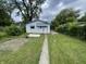 Full view of the shed featuring a white door, blue trim, and surrounding green bushes at 1021 W 37Th St, Indianapolis, IN 46208