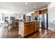 Open-concept kitchen with a granite island, stainless steel fridge, and wood cabinets at 1065 Park Ct, Avon, IN 46123