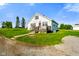 Charming white farmhouse featuring a red door and a spacious front yard on a sunny day at 10758 W State Road 142, Quincy, IN 47456