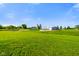 Exterior view showcases a home, outbuilding, and expansive green lot under a bright blue sky at 10758 W State Road 142, Quincy, IN 47456