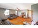 Comfortable living room with a plush reclining sofa, hardwood floors, ceiling fan, and natural light from the window at 10758 W State Road 142, Quincy, IN 47456