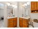 Bathroom featuring dual sinks with wood cabinets, mirrors, and updated fixtures at 11061 Mast Ct, Fishers, IN 46040