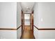 Hallway view featuring hardwood floors, wood trim, and open view of a laundry room at 11469 Woodview Ct, Fishers, IN 46038