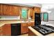 Close up view of the kitchen featuring wood cabinetry, tile backsplash, and black appliances at 11469 Woodview Ct, Fishers, IN 46038